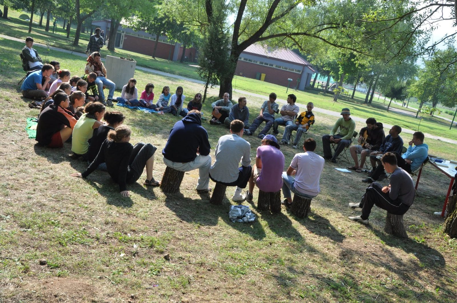 A group seated in a circle outdoors with open Bibles