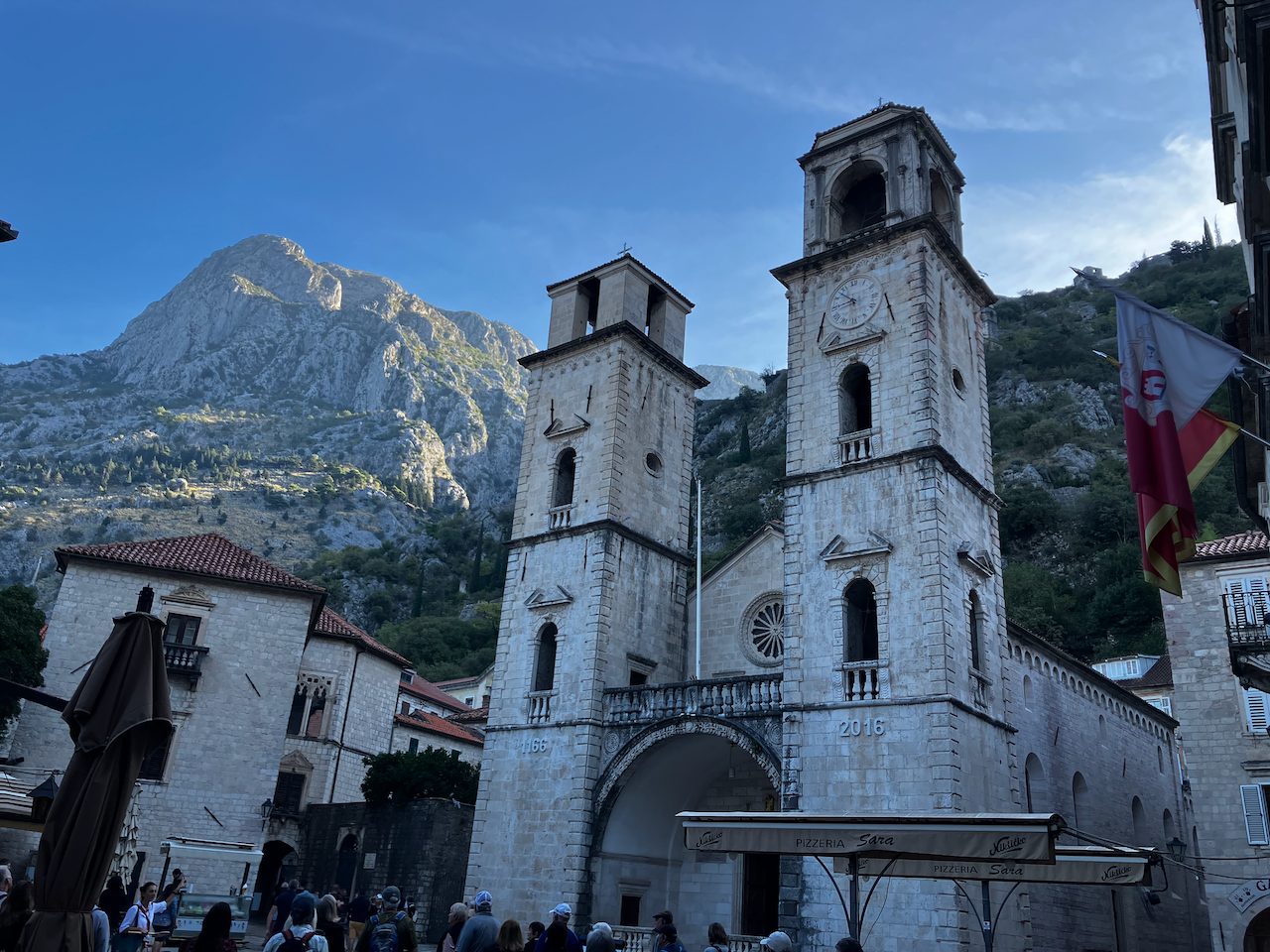 A stone cathedral with twin towers below a mountain