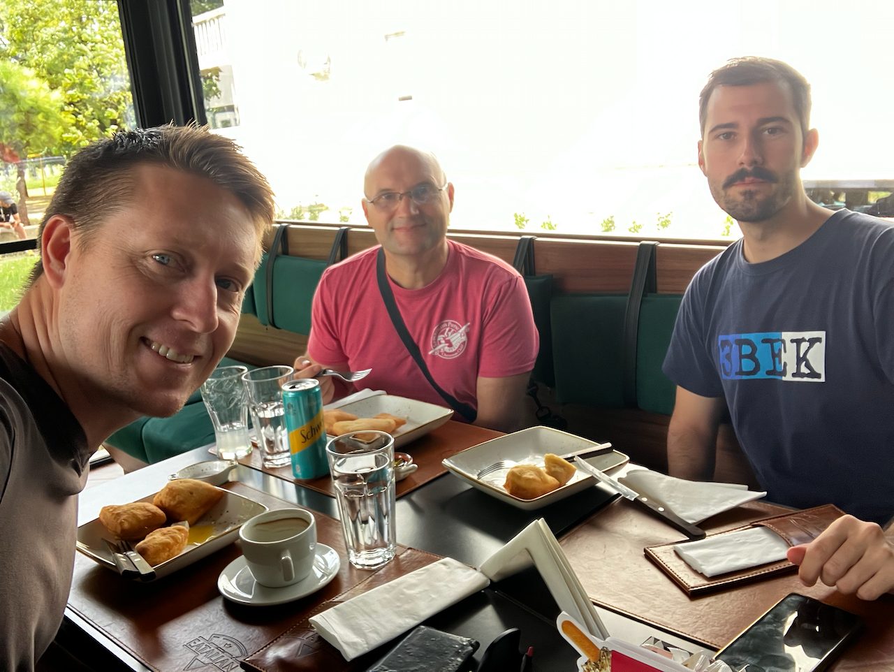 Three men talking together over coffee around a table