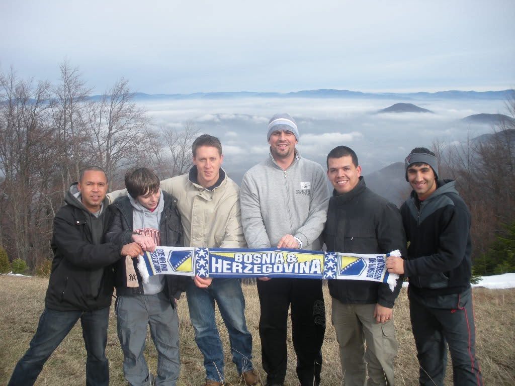 A group of men standing on a mountainside above the clouds